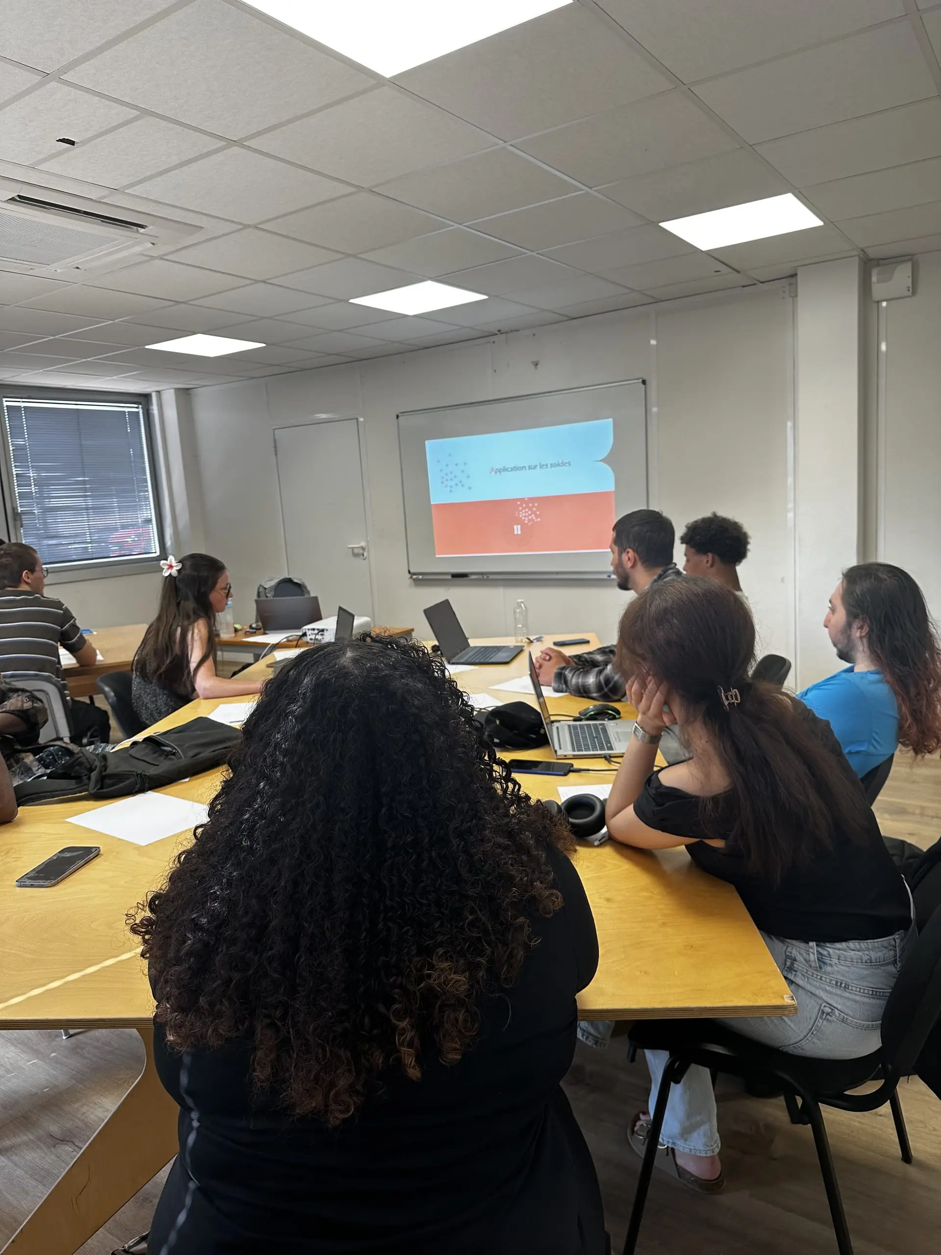 Apprenants réunis en salle de formation devant une présentation sur l'application des soldes