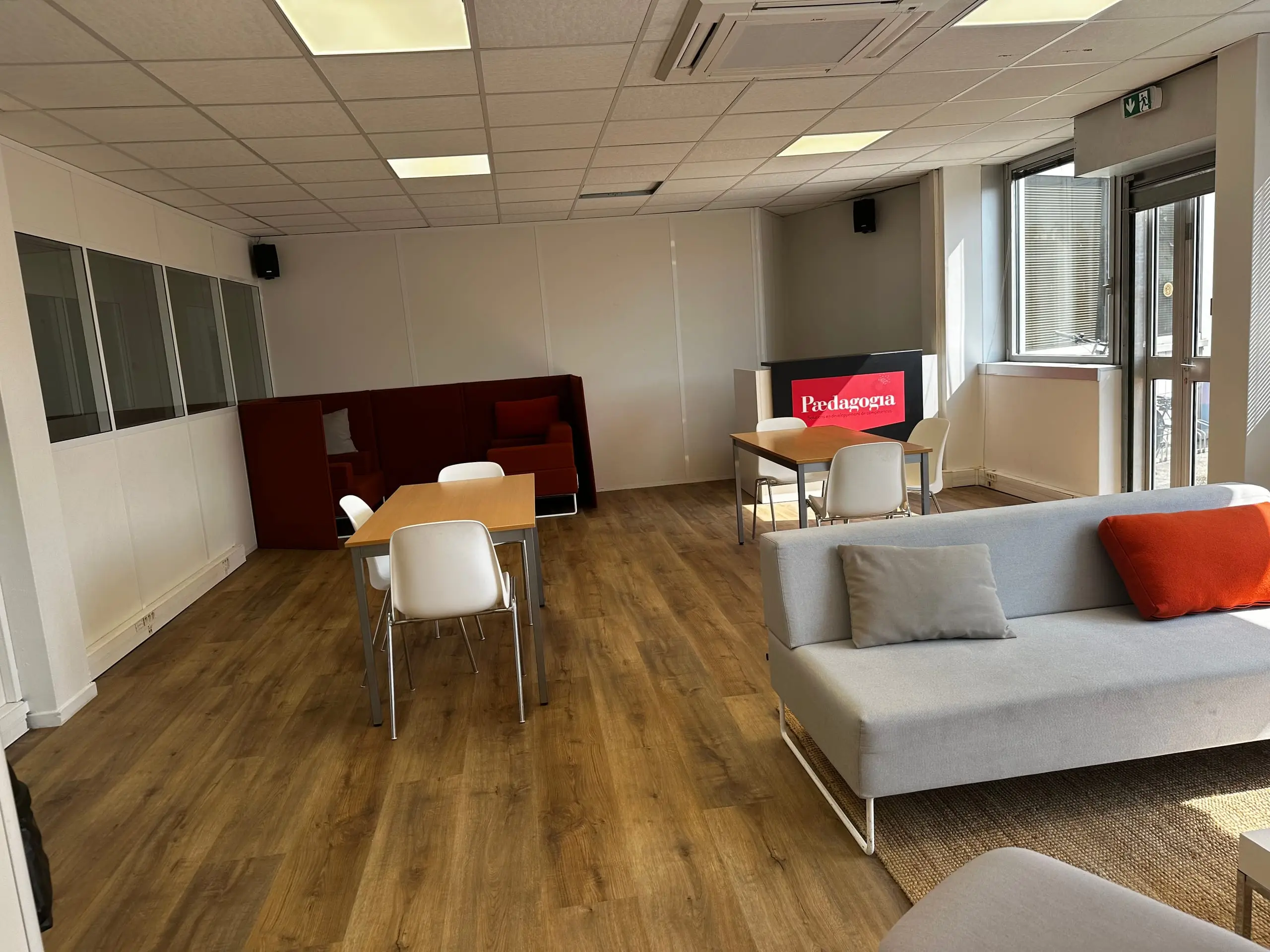 Espace commun du CFA Paedagogia avec canapé, tables de travail et écran mural