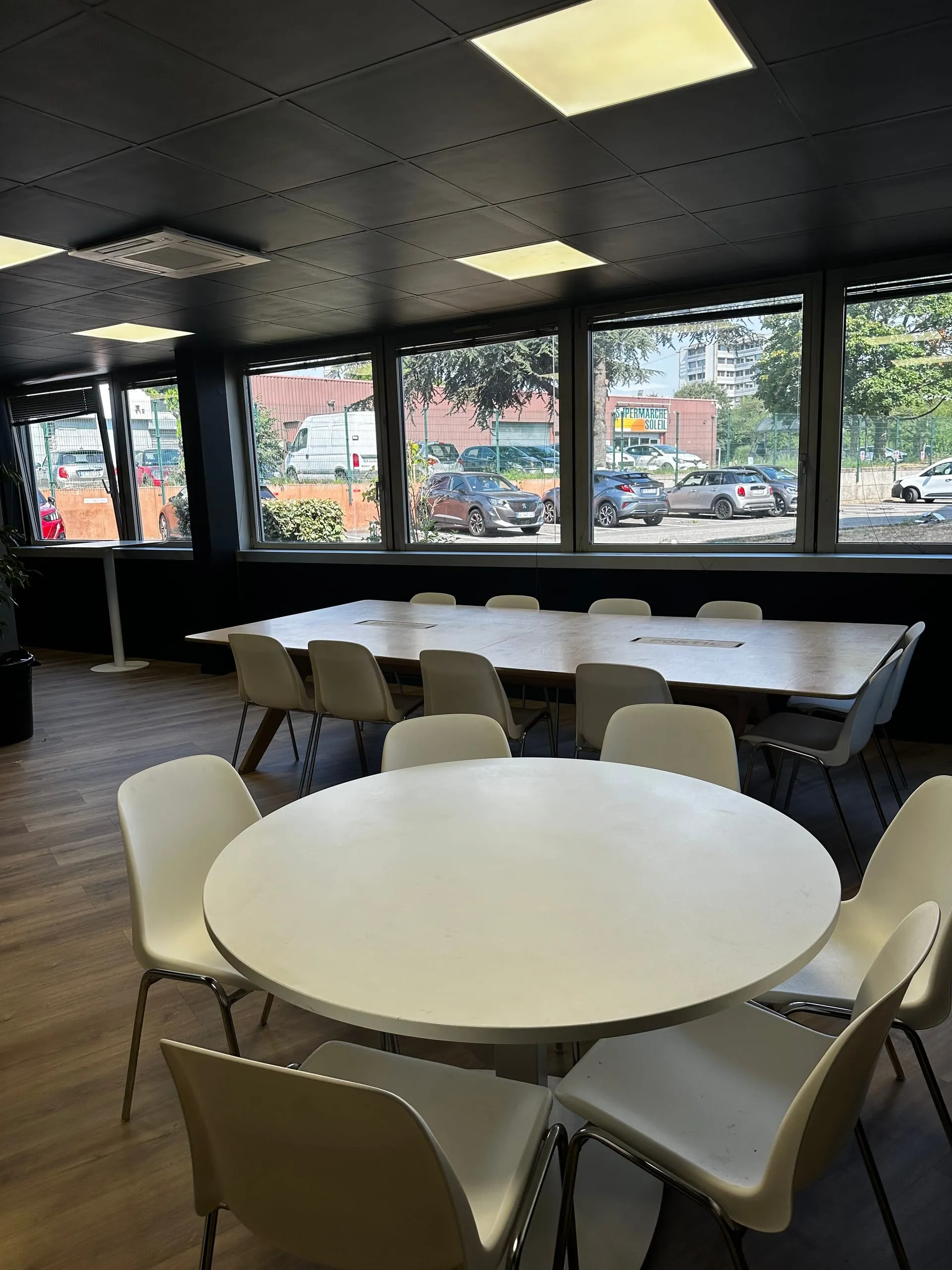 Salle de réunion du CFA Paedagogia à Toulouse avec une grande table rectangulaire, une table ronde et des chaises blanches.