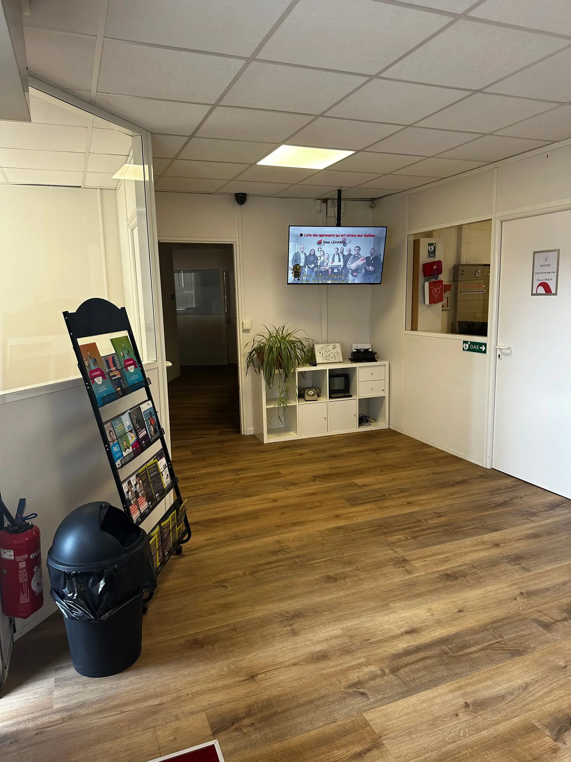 Hall d'accueil du CFA Paedagogia avec présentoir à brochures et écran mural