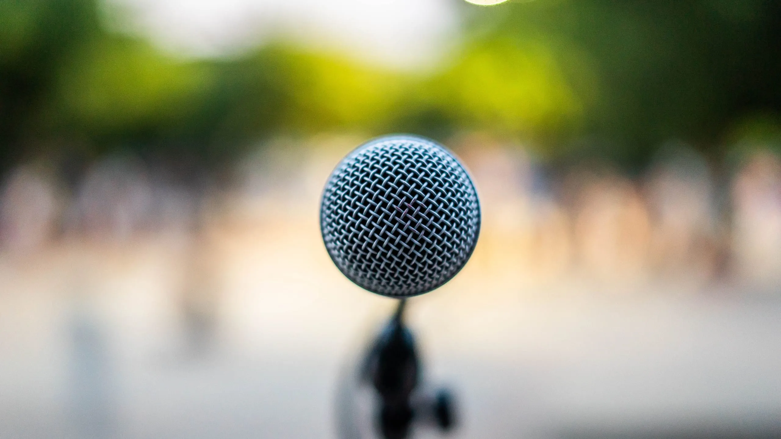 Microphone noir en gros plan devant un arrière-plan végétal flou