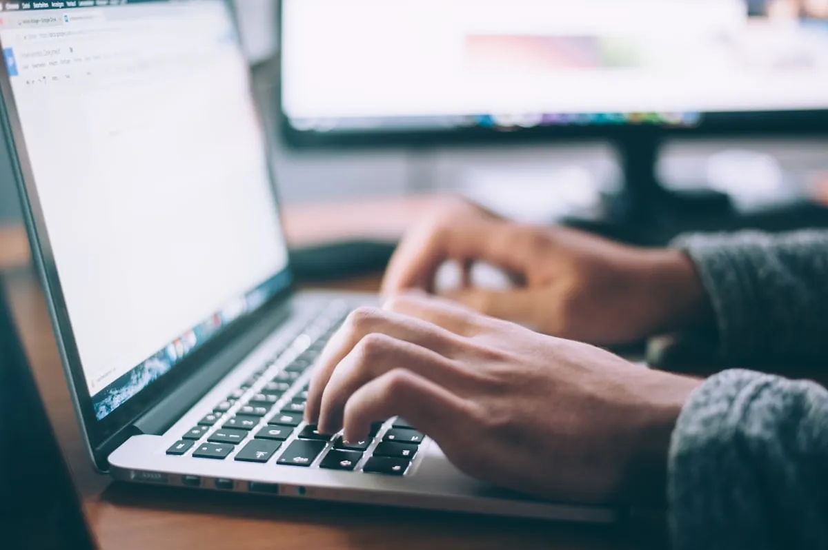 Mains tapant sur le clavier d'un ordinateur portable lors d'une session de travail numérique en entreprise