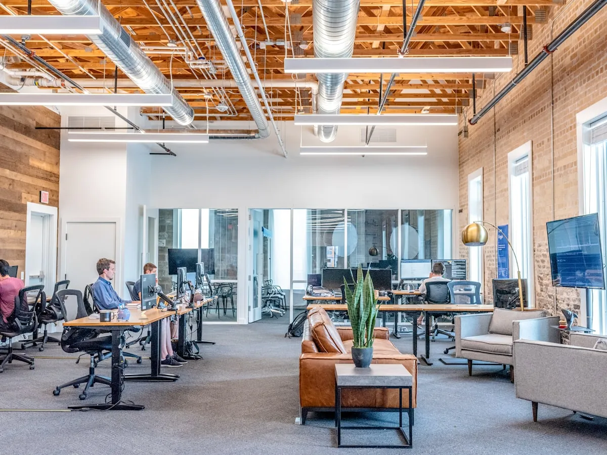 Professionnelle debout face à son équipe, présentant des idées lors d'une réunion de travail dans une salle lumineuse